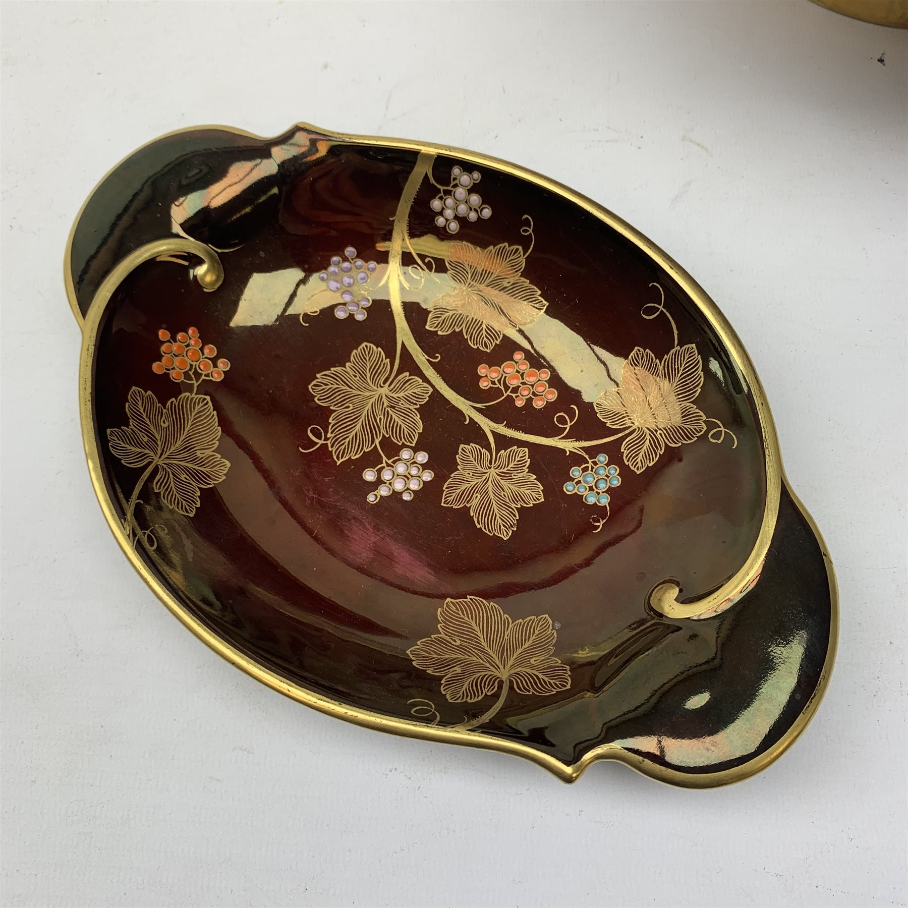 A large Carlton Ware Rouge Royale bowl, the interior decorated with dragonflies, lilies and bulrushes in enamel and gilt, with marks beneath, D25.5cm, together with a Carlton Ware Rouge Royal dish, decorated with grape vines, with marks beneath, L21.5cm. 