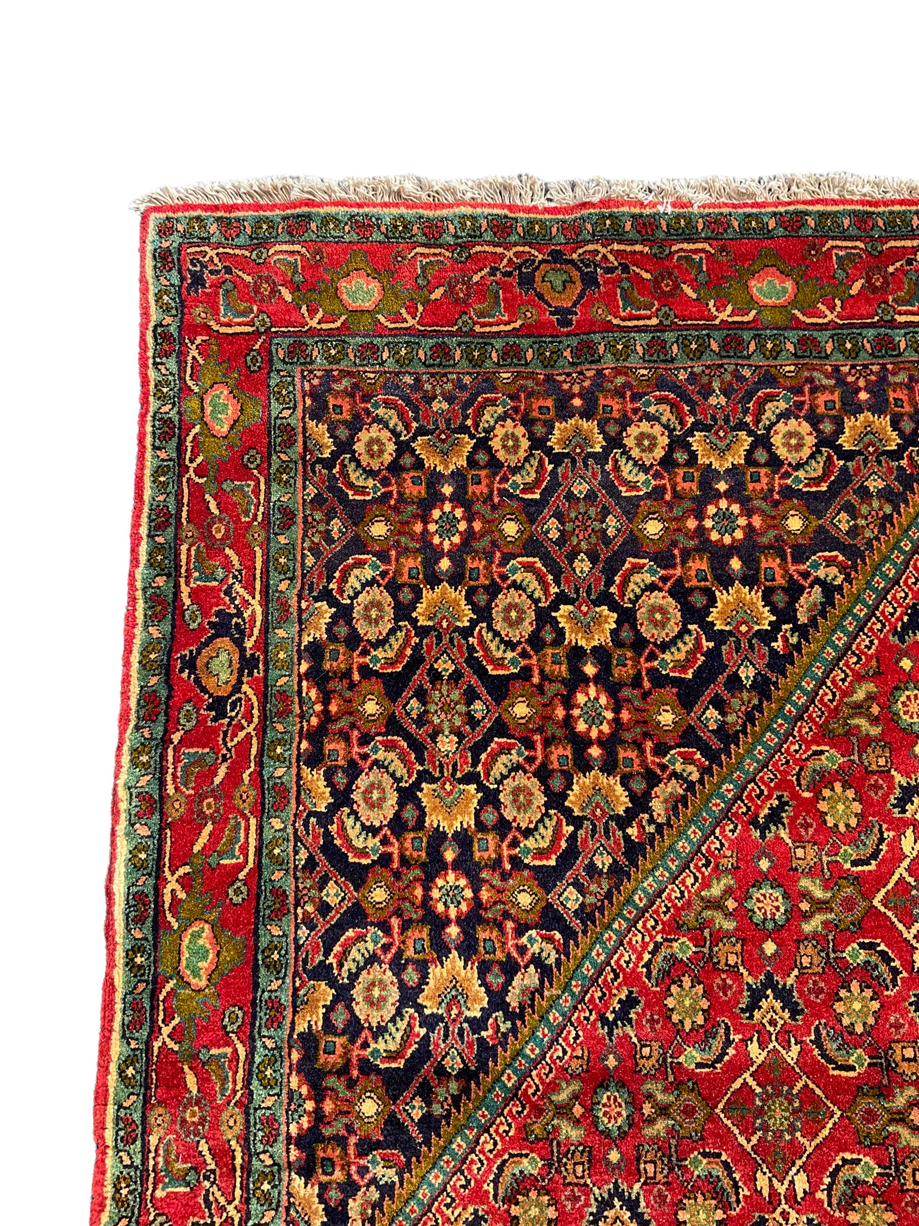 Persian Bijar red and blue ground rug, central panel decorated with tree of life and flower head motifs, decorated all-over with Herati motifs, triple band band border decorated with stylised plant motifs