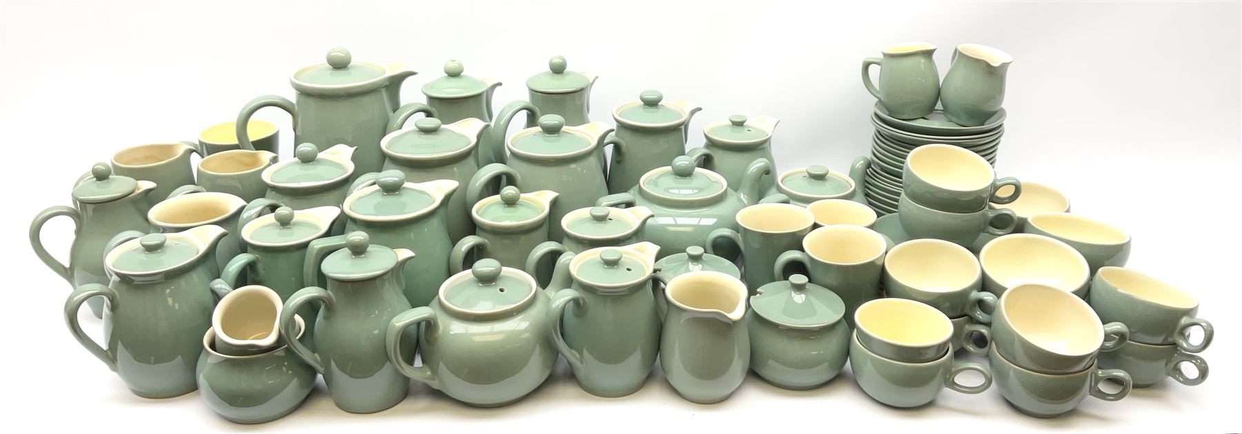 Denby Manor Green pattern tea service, comprising of three teapots, twelve coffee pots of various sizes, four hot water jugs with lids, seven jugs, eleven teacups, four mugs, seventeen saucers, six sugar bowls, two sugar bowls with lids and eleven side plates.  