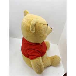 Very large plush covered figure of Winnie The Pooh in a seated position with black plastic eyes, black felt nose and eyebrows, red open mouth and T-shirt with name to front H42