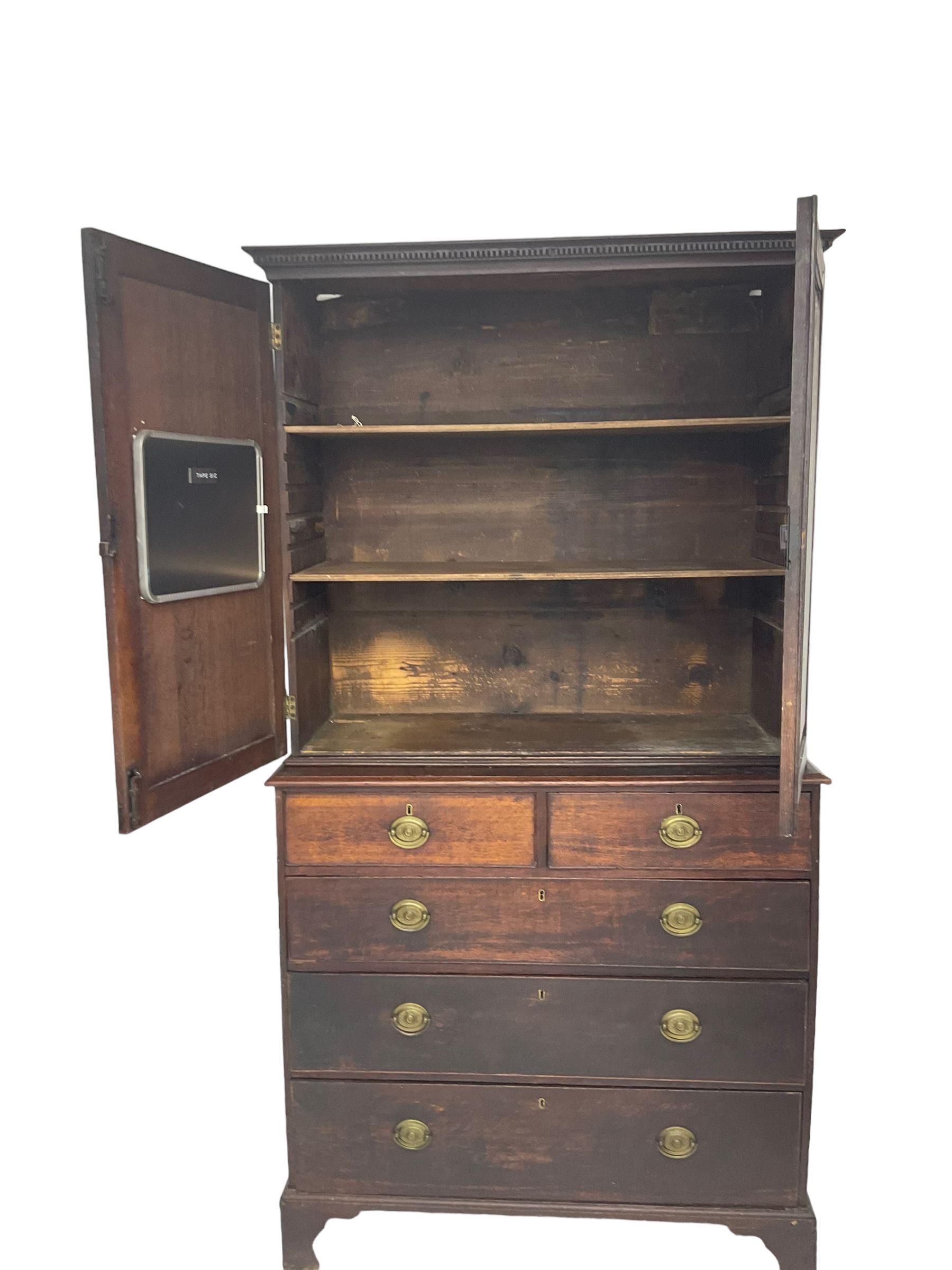 George III oak linen press, projecting cornice with dentil moulding over two panelled doors enclosing two adjustable shelves, fitted with two short over three long drawers, raised on bracket feet