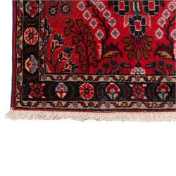 Two Persian rugs, the larger with a crimson field decorated with three linked indigo medallions amongst flowering tendrils, shaped floral spandrels and an indigo palmette border, (161cm x 129cm), the smaller with a crimson field centred by an ivory rosette amongst stylised flowering plants, within a dark floral border, (114cm x 79cm) (2)