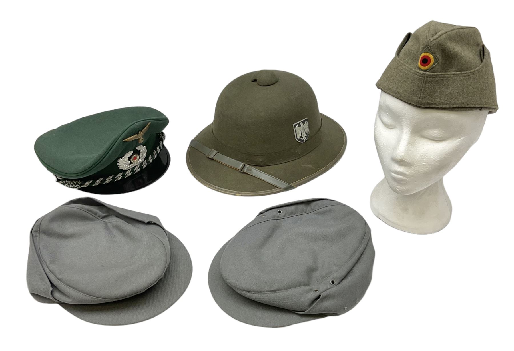 Five reproduction German WW2 hats comprising Wehrmacht olive tropical helmet, Heer officer's peaked cap, two M43 caps and Field side cap (5)