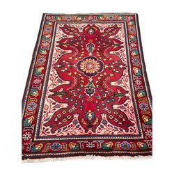 Persian Azerbaijan crimson ground rug, the field decorated with central floral motif and surrounded by trailing floral branches, enclosed within a shaped outer band with further floral decoration, the border with repeating flower heads, geometric guard stripes 