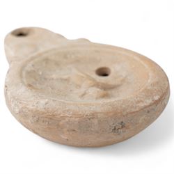 Roman terracotta oil lamp with Cupid motif c.1st-2nd Century AD, mould-made, with a rounded body and volute nozzle, the concave discus decorated in relief with a figure of Cupid in motion, depicted with wings and bow, within a raised circular border, with central fill-hole and wick-hole at the nozzle W 8.5cm
Provenance: By the vendor’s repute, acquired/collected in the Middle East (Dead Sea area/Syria) in the 1960s