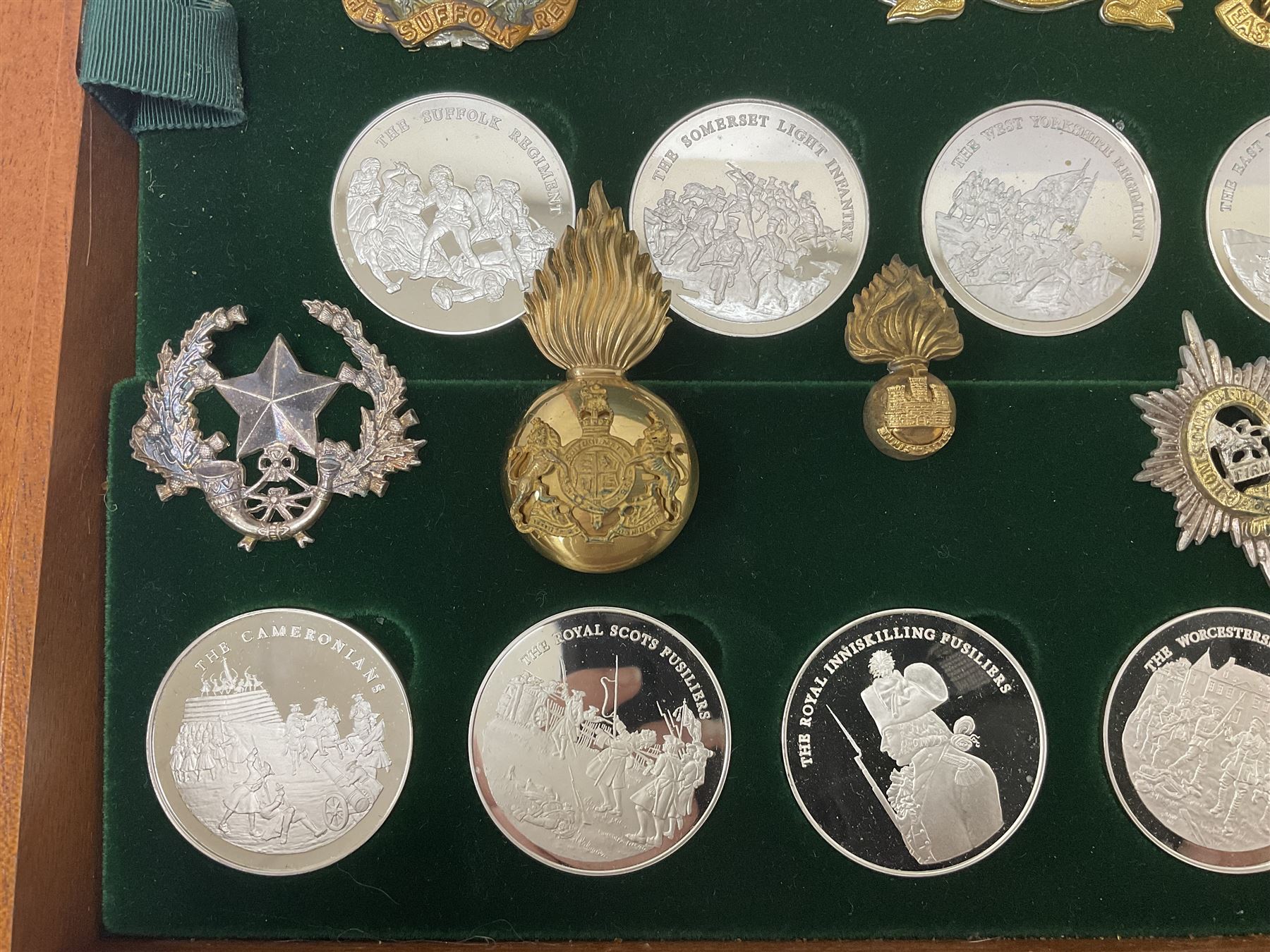 Great British Regiments, 1977, set of fifty two frosted silver medals by the Birmingham Mint, each bearing the name of a regiment with a depiction of an action on the obverse and further details on the reverse, all hallmarked Birmingham Mint, assay offices and dates; together with 52 base metal copy cap badges for each regiment, all housed and mounted on two trays and contained within a wooden presentation case, with brass plaque and fittings, lock and key, with a certificate of authenticity 