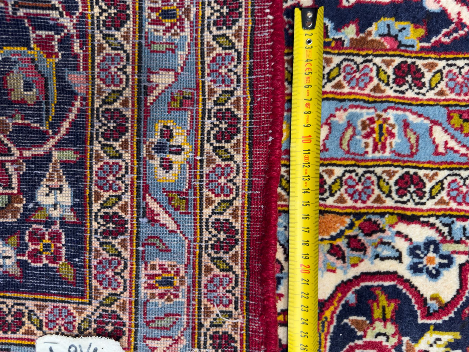 Central Persian Kashan hand-knotted carpet, the madder red field with central lobed medallion in indigo and ivory, enclosing scrolling arabesques and flowerheads, framed by palmette spandrels and an indigo border of rosettes and lotus forms between multiple floral guard stripes, from the region of Kashan