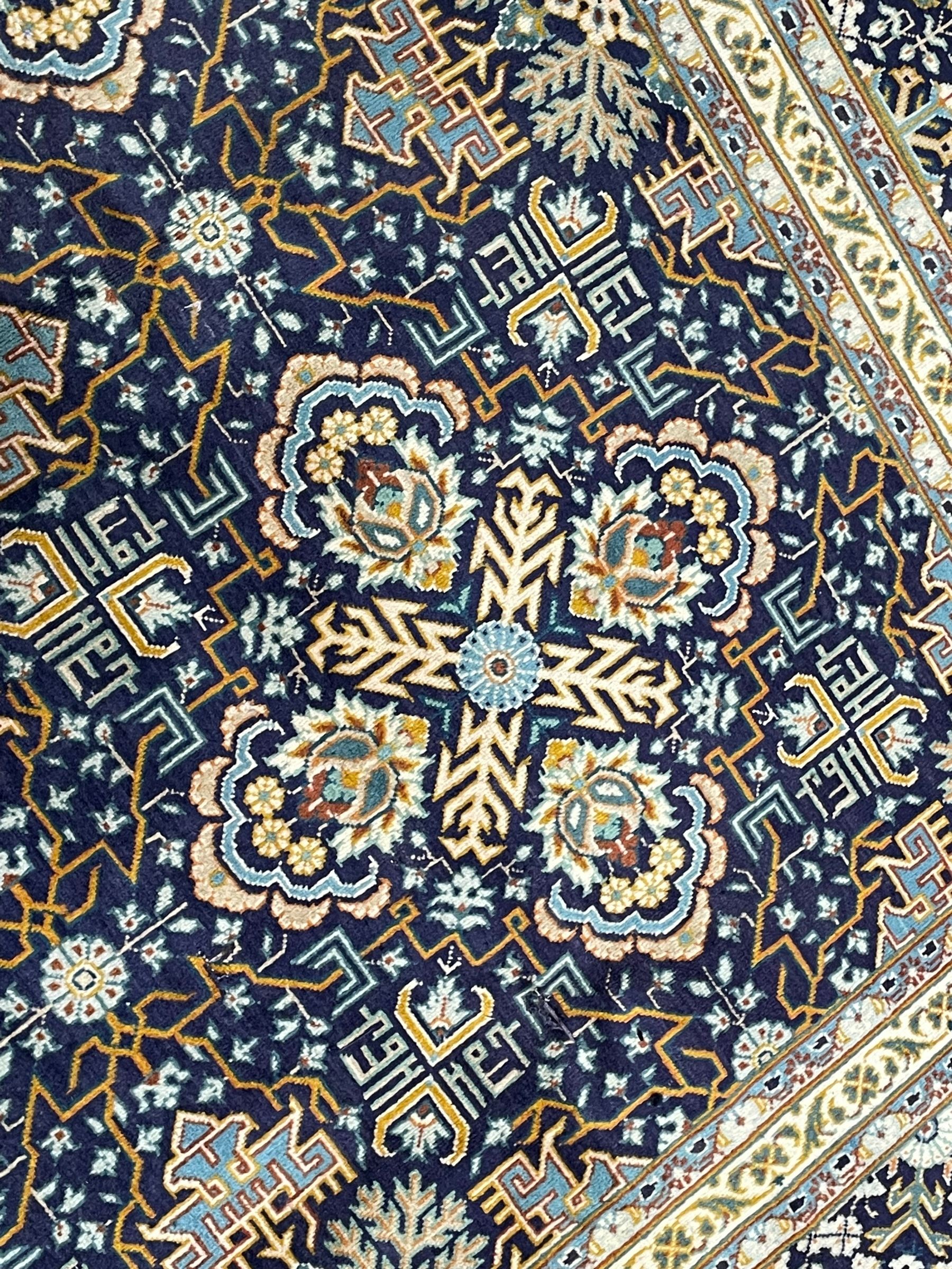 Persian indigo and pale gold ground rug, overall busy geometric design, the field decorated with hooked Hac and palmette medallions surrounded by densely patterned zig-zags and stylised foliate motifs, the border decorated with smaller Hac motifs, within multiple guard stripes 