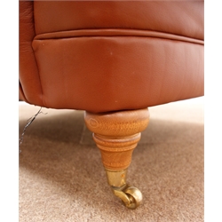  Howard style armchair, upholstered in a chocolate brown leather, turned supports on castors, W80cm  