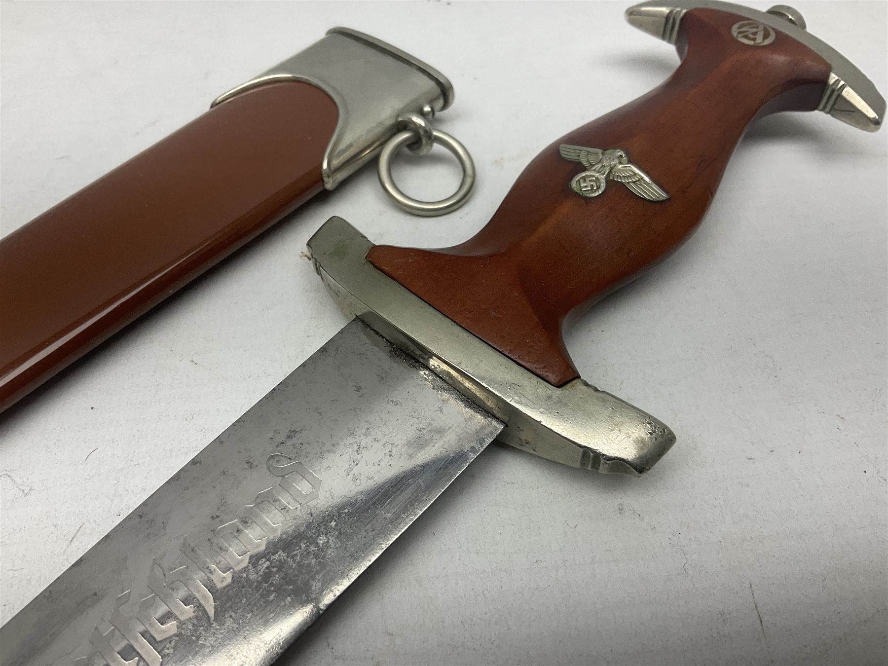 WW2 German SA dagger the 22cm double edged steel blade by G. Felix Gloriawerk Solingen inscribed 'Alles Fur Deutschland', the cross-piece impressed with the SA Gruppen mark Nm verso for Nordmark, wooden grip inset with eagle and SA emblem; in brown painted scabbard with nickel mounts L37cm overall