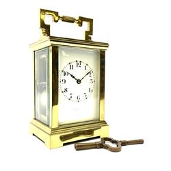 Early 20th century brass and bevelled glass carriage clock, angular handle with reeded cylindrical centre piece, the Arabic dial signed 'Goldsmith & Silversmith Co. Ltd, 112 Regent Street, London', twin train driven movement striking the hours and half on coil, with presentation inscription to top