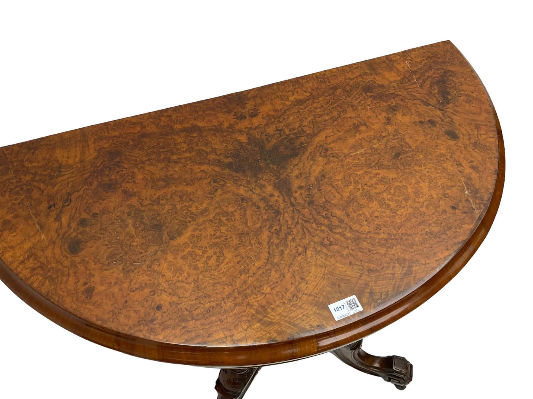 Victorian figured walnut demi-dune card table, the fold-over moulded top with circular baize lining, on four turned pillars with central finial platform, four splayed moulded supports with angular scrolled feet, on castors