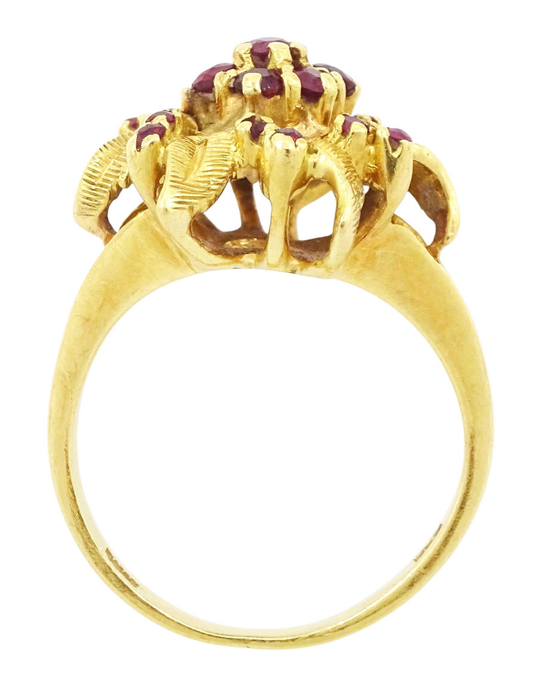 18ct gold ruby flower head cluster ring, seven round cut rubies surrounded by textured leaves, each spaced by two rubies, stamped 750