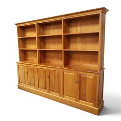 Philip Koomen (1953-) - Craftsman-made modern cherrywood large open
bookcase with a cupboard base, upper section with a
shaped cornice above three sections with two open
shelves, the lower section has three cupboards,
each with two panelled doors enclosing a single
shelf, raised on a plinth base