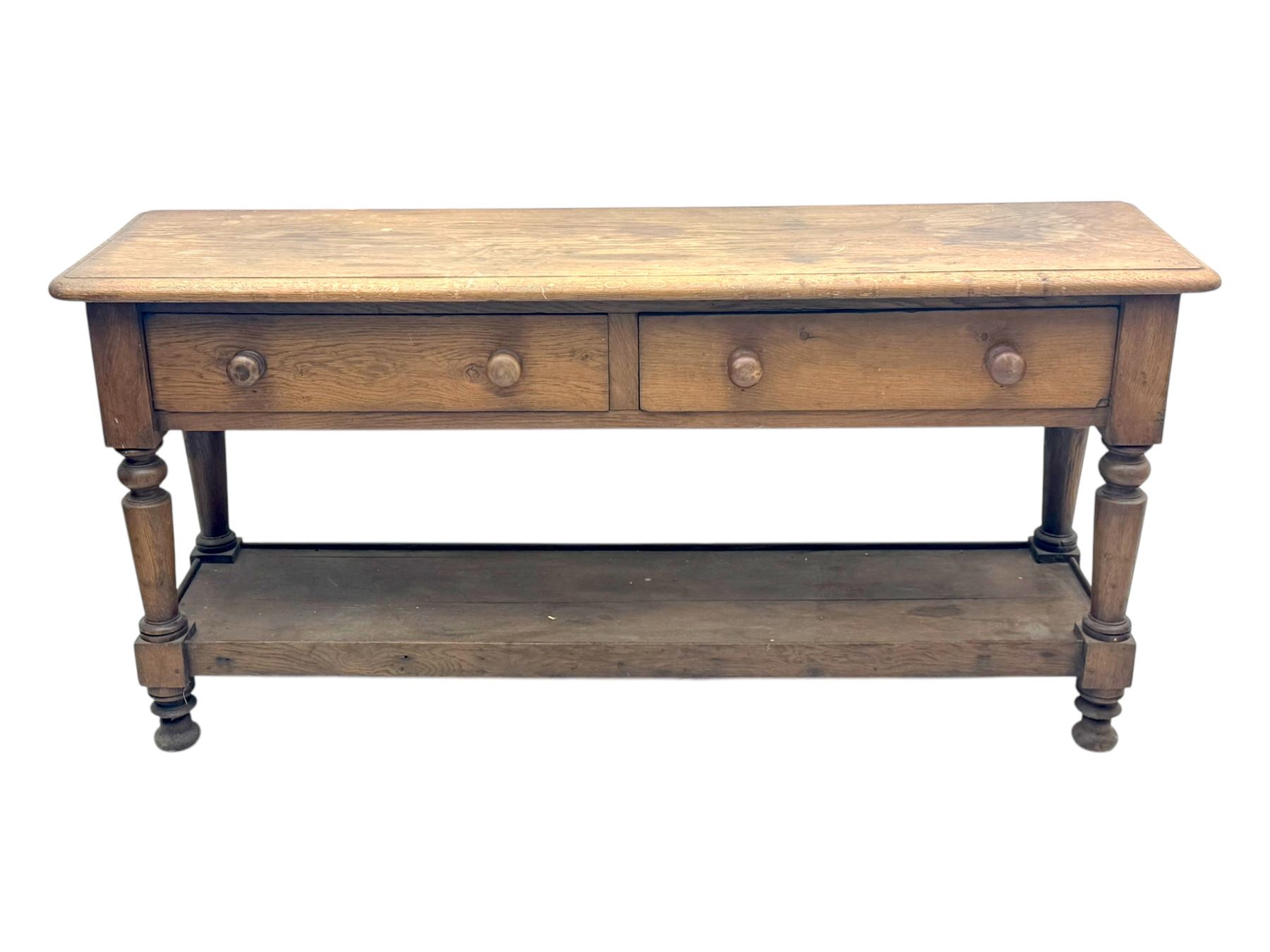 Late 19th century oak potboard dresser base, rectangular top over two frieze drawers with turned wooden handles, raised on four ring turned and tapering supports with block feet, united by a full-width lower potboard