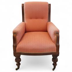 Victorian mahogany framed armchair, upholstered in salmon pink dot patterned fabric, the moulded arms with carved scroll terminals, raised on turned and fluted front legs and swept back legs, all with castors