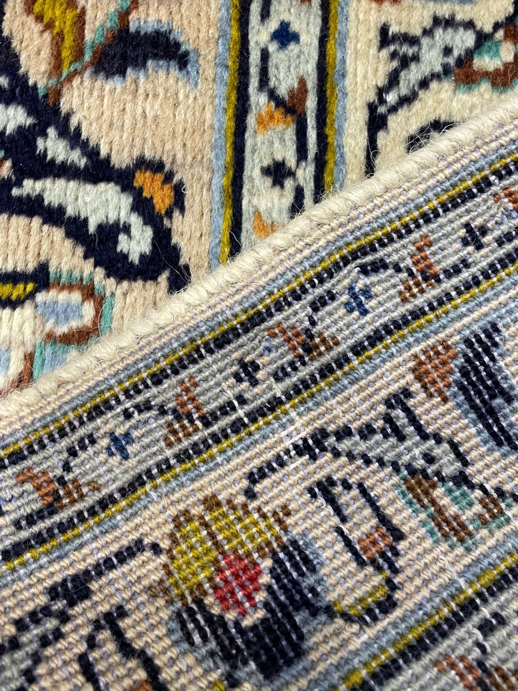 Persian Kashan Ivory ground carpet, the busy field decorated all over palmettes and trailing branches, scrolling border interspersed with stylised plant motifs, within guard stripes