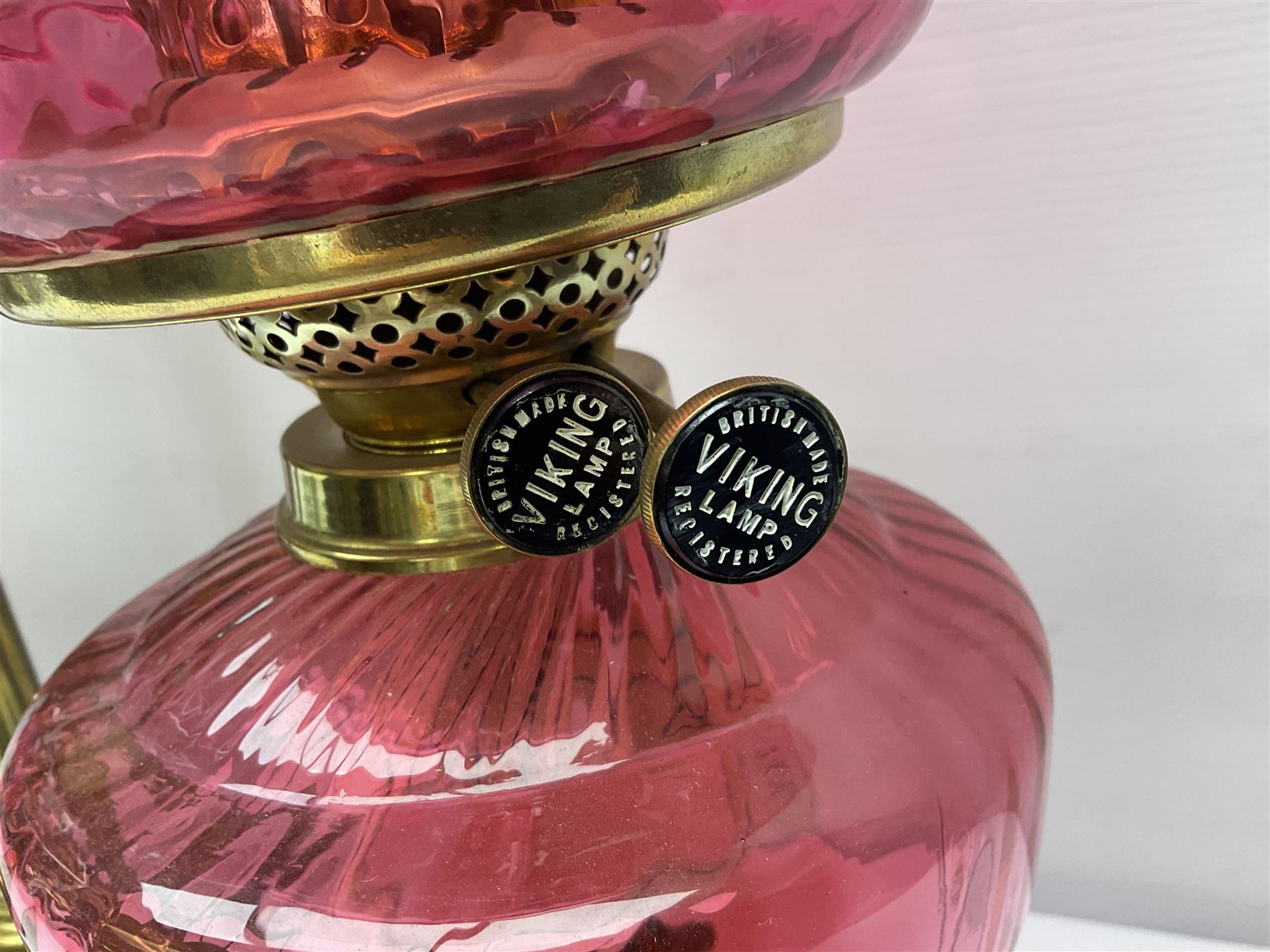 Victorian cast brass oil lamp, with fluted pink glass shade, together with two smaller brass oil lamps with pink shades and reservoirs and a pair of oil lamps, the bases modelled as putti, with pink glass reservoir  and frosted shades, tallest H70cm