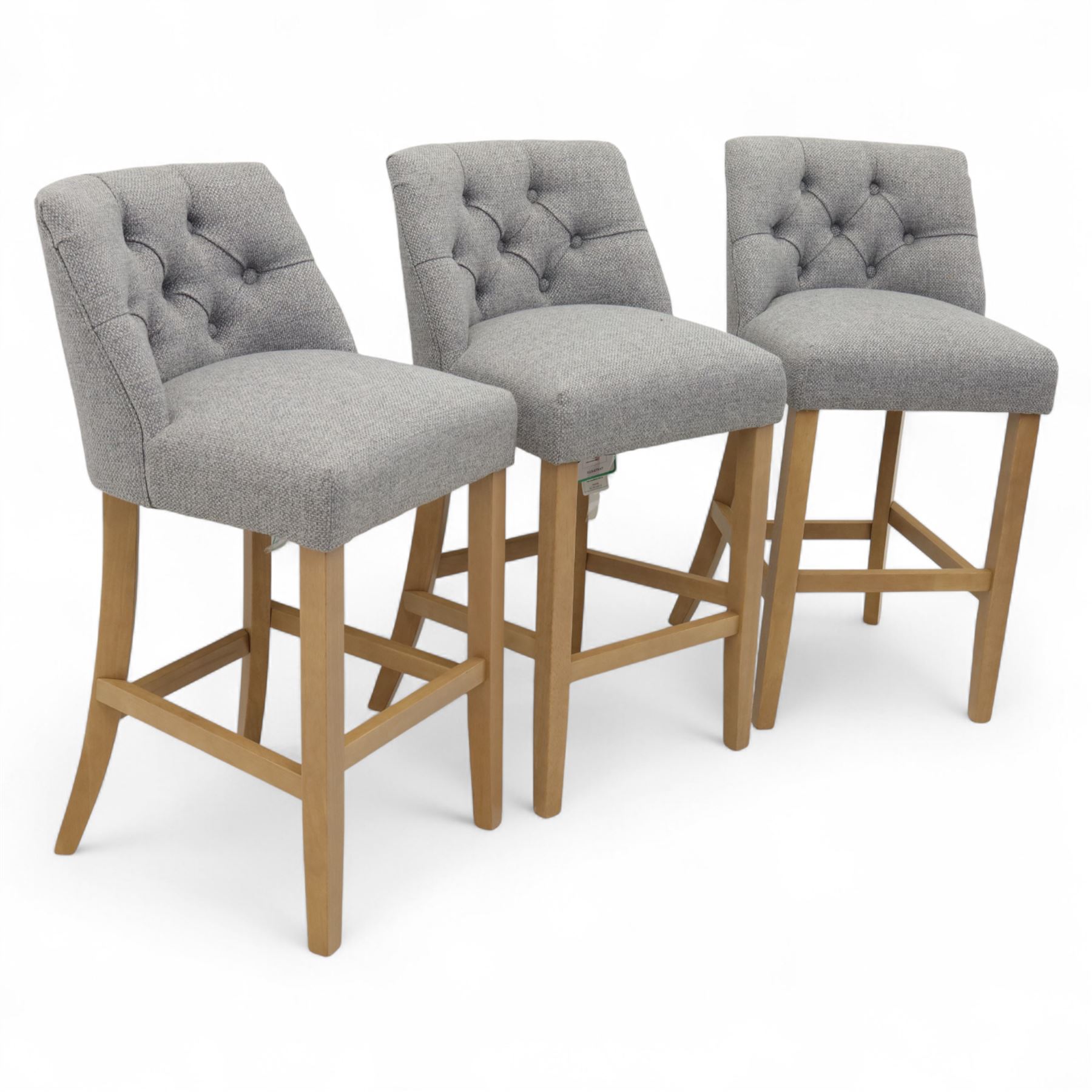 Contemporary set of three upholstered bar stools, each with button-tufted grey fabric backrest and seat, raised on light oak finish square legs united by stretchers