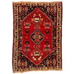Turkish red ground rug, the three central geometric medallions within indigo spandrels, ivory border with repeating stylised plant motifs