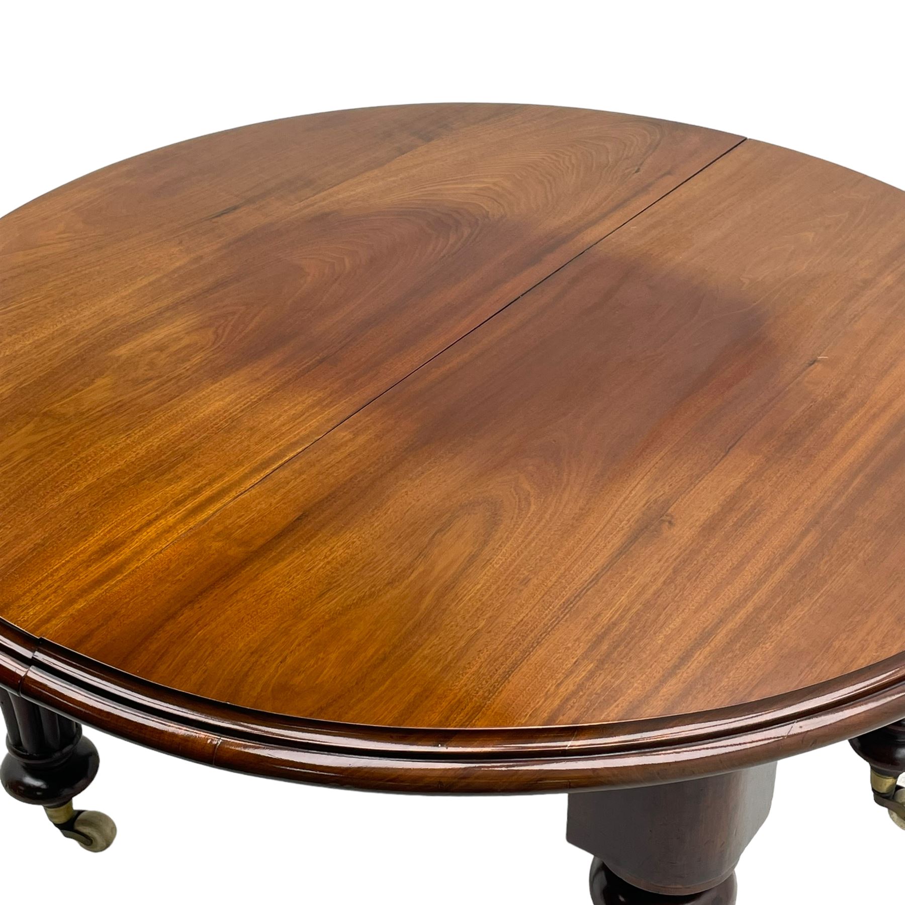 Victorian mahogany extending dining table, circular telescopic extending top with moulded edge, two additional leaves, on turned and lobe carved supports with brass and ceramic castors 