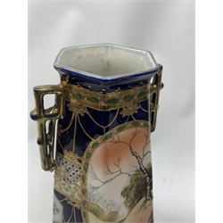 A pair of Japanese Nippon Kinjo vases, of tapering hexagonal form with twin stylised handles, the cobalt blue ground with oval hand painted panels to front and verso depicting landscapes, further detailed with smaller floral bands and panels and heightened with gilt, each with mark beneath, H30.5cm.  