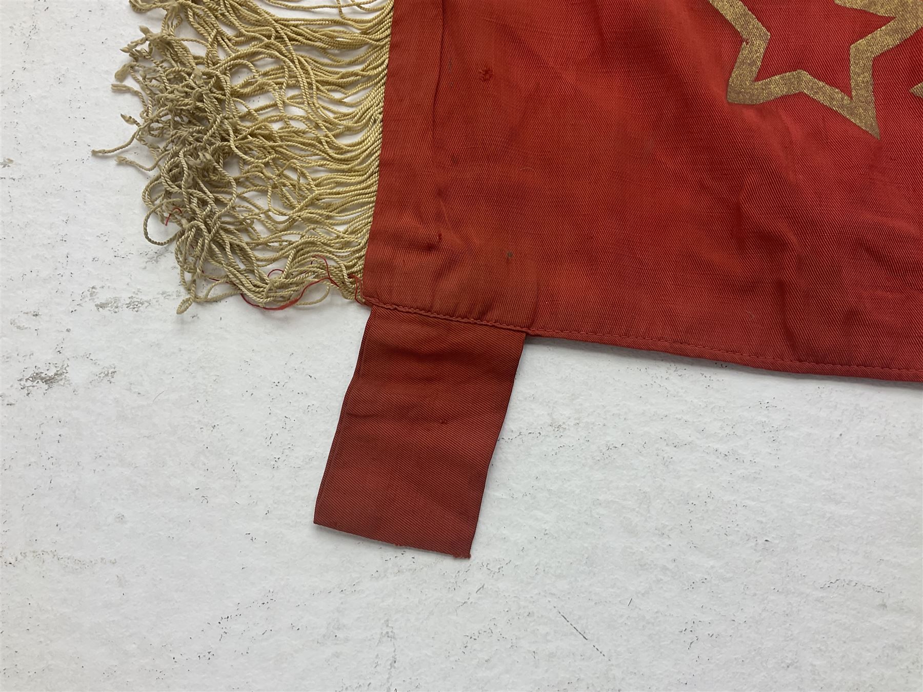 1970s Soviet banner printed in gold on a red ground, roughly translates as 'Transferable Banner - To the winner in the Socialist Competition' and 'Work Study Live by Communism' verso; wreath of wheat ears to either side; tassels on three sides 110 x 155cm