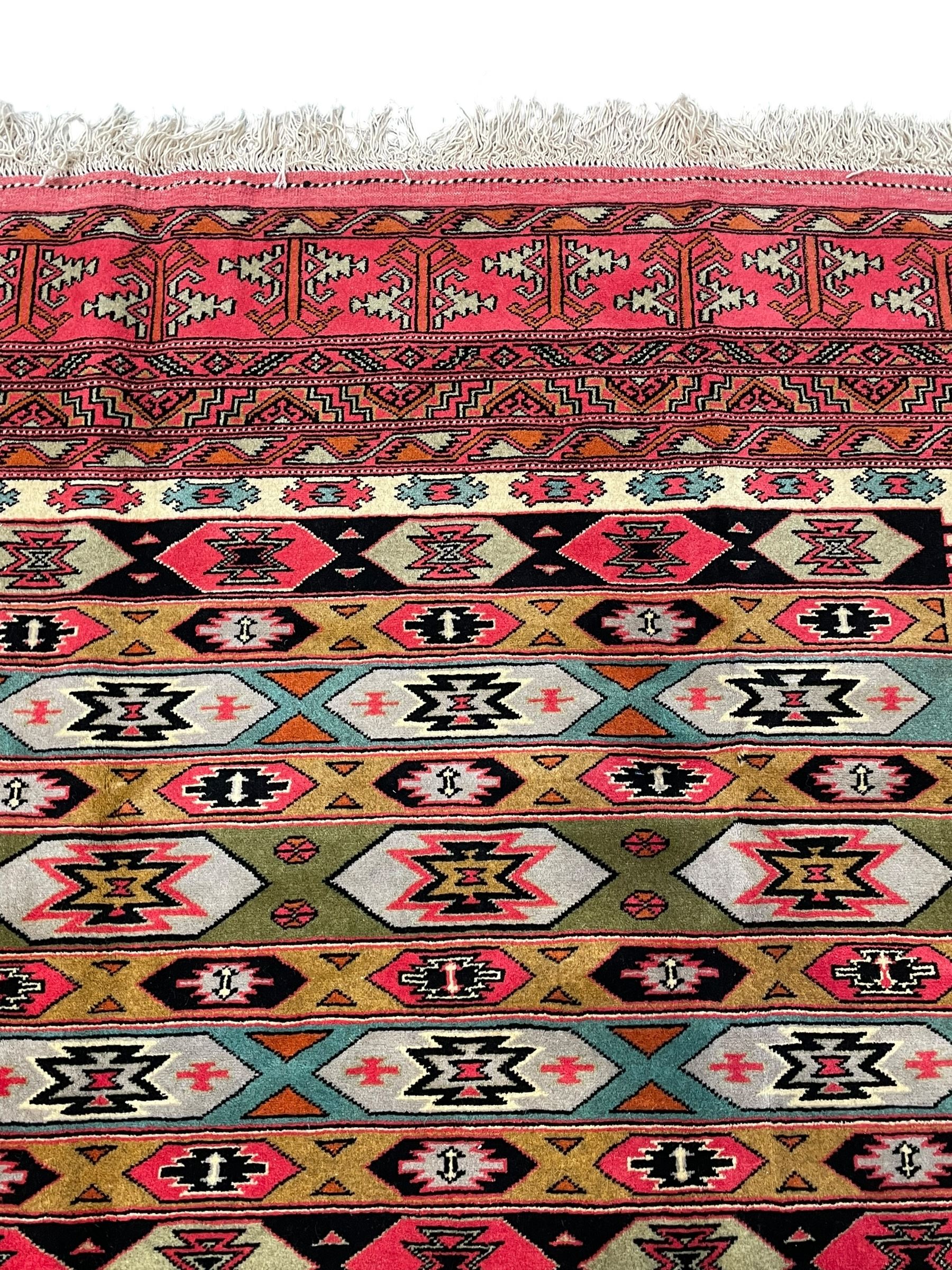 Turkaman red ground rug, the field divided into horizontal rows and decorated with geometric motifs, intricately pattern borders and end panels