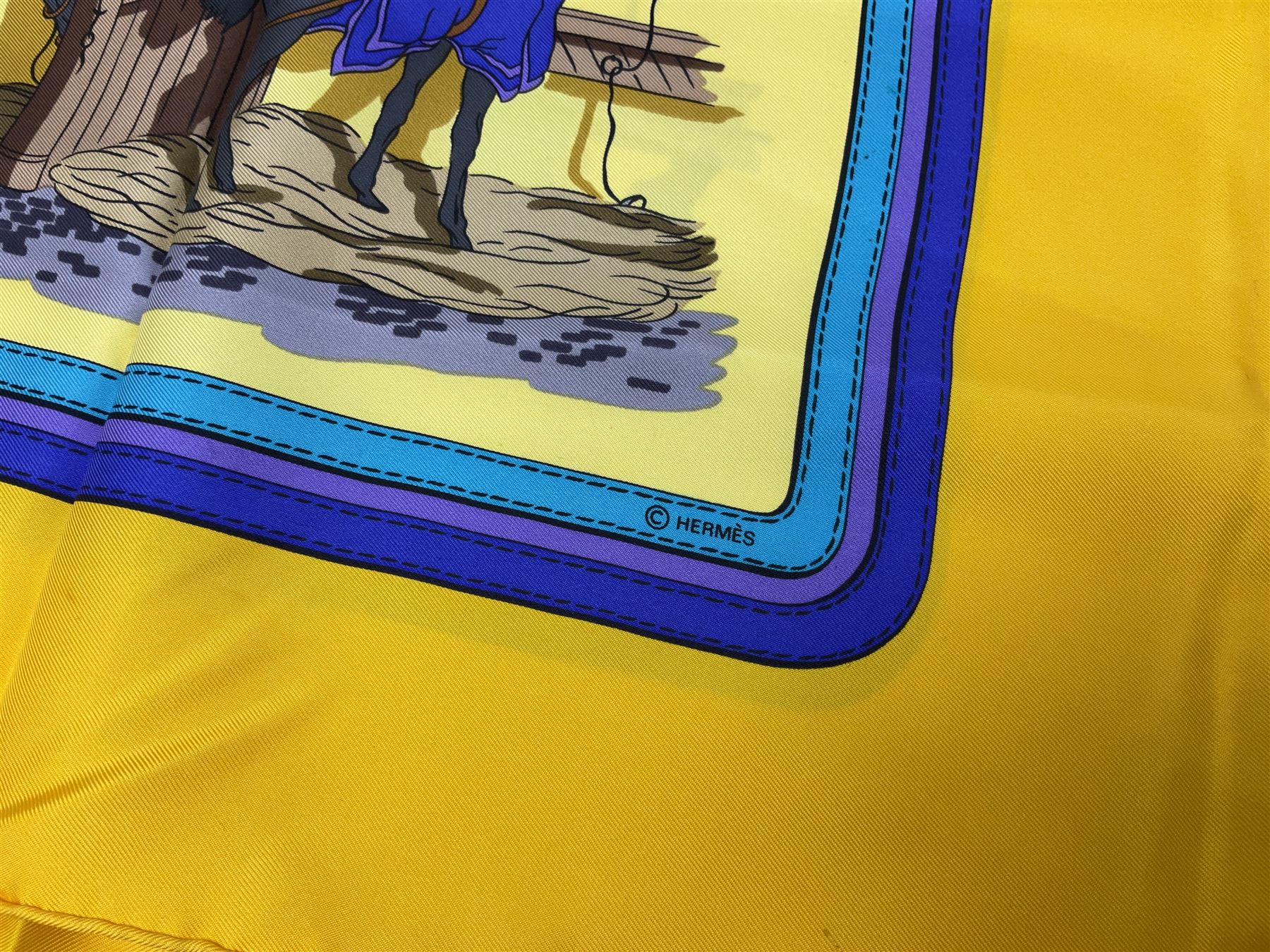 Hermès 'Ecuries' silk scarf, designed by Hugo Grygkar in 1947, printed with twenty horses in their respective stables, on yellow ground contained within stitched effect blue and purple and darker yellow gold borders, with rolled hand stitched edges and Hermes material label, 87cm square