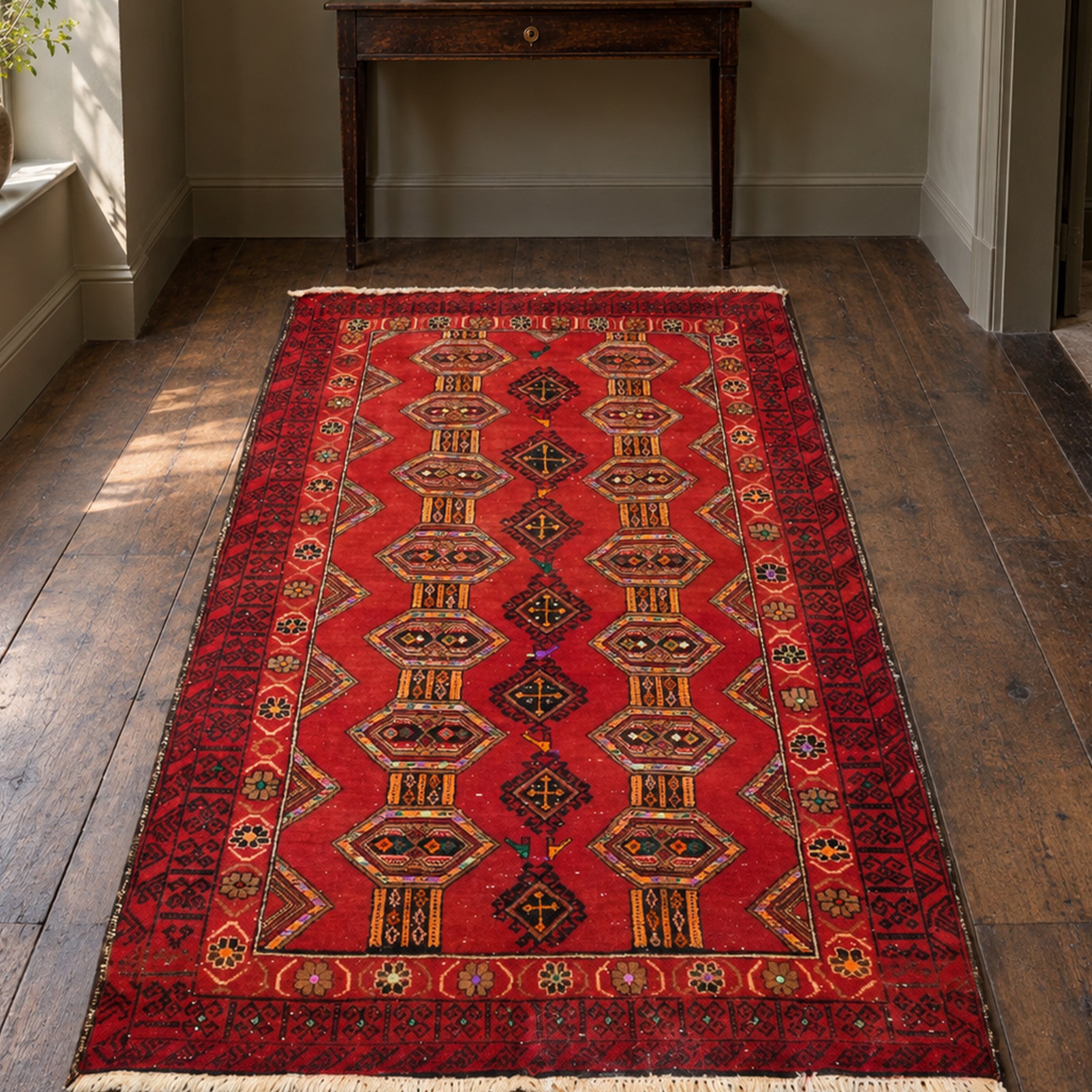 Persian Baluchi crimson ground rug, decorated with three columns of geomtric motifs