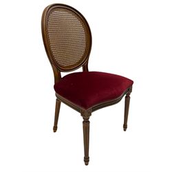 Set six French style walnut finish dining chairs, oval cane bergere backs over serpentine seats upholstered in red, flower head carved fluted supports
