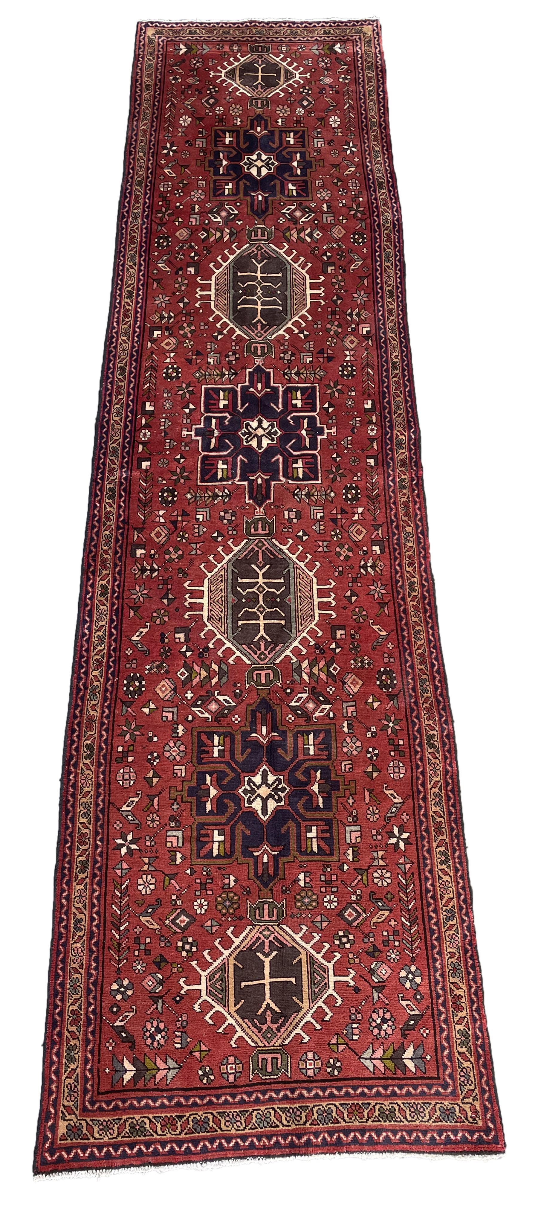 Persian Karajeh red ground runner, decorated with multiple stylised medallions and motifs