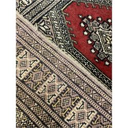 Persian peach and red ground rug, the field decorated with canted rectangular panels, repeating stylised floral design border (94cm x 63cm); and a similar rug signed by the weaver (90cm x 63cm)
