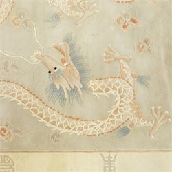 Chinese wool rug, the pale grey central field decorated with two stylised dragons, flaming pearls and cloud scrolls, within a cream border of shou medallions and geometric motifs, with cotton fringe ends