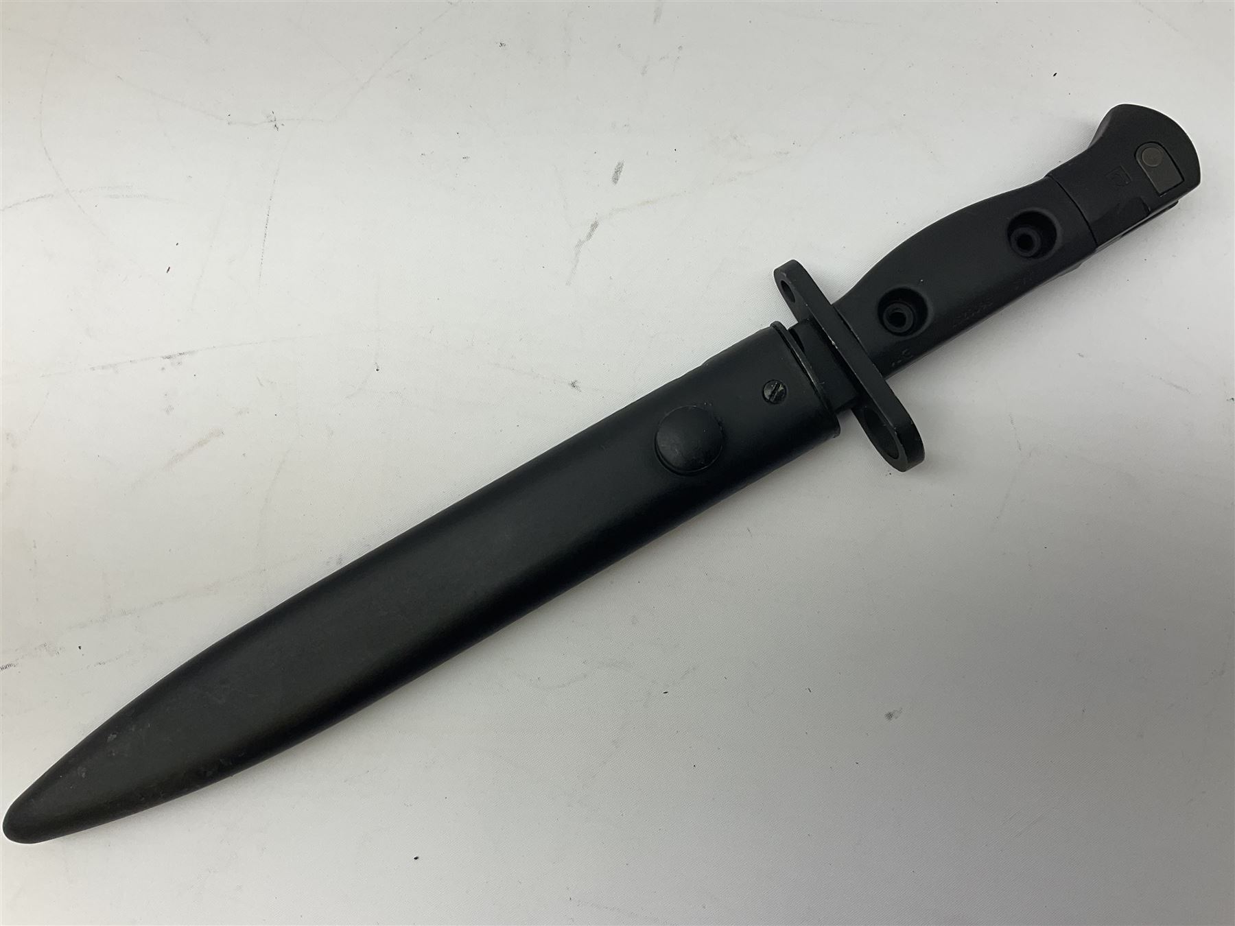 British Army L1A3 SLR Self Loading Rifle bayonet, with 20.5cm Bowie type fullered blade, hooked pommel with working push release button, grip secured by two deeply recessed rivets and marked L1A3 9600257 D71; in matching black scabbard L32.5cm overall