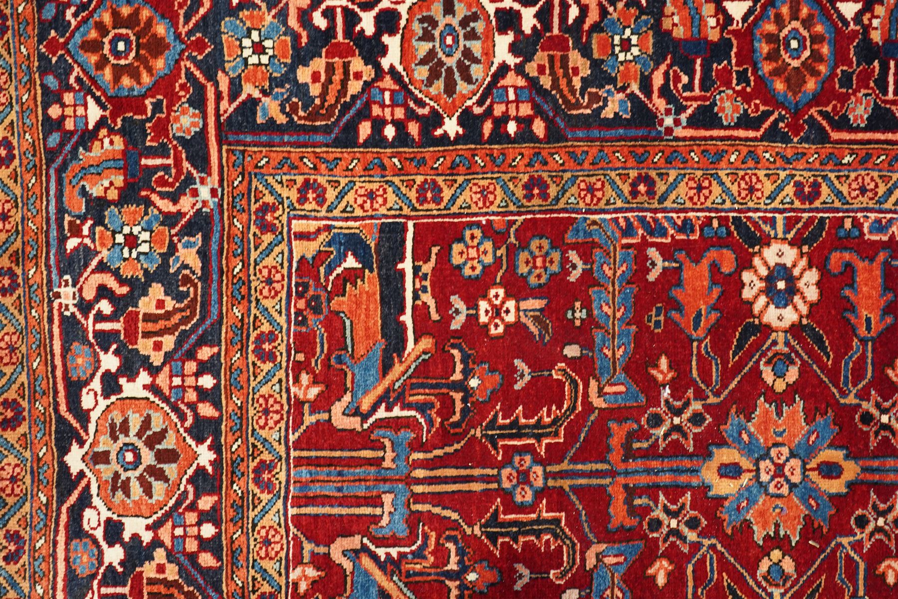 North West Persian Karadja hand-knotted carpet, deep red field decorated with an all-over lattice design of elongated geometric devices interspersed with rosettes and angular palmettes, enclosed by a dark indigo main border of stylized floral and geometric motifs between multiple guard stripes, with cotton fringe ends 