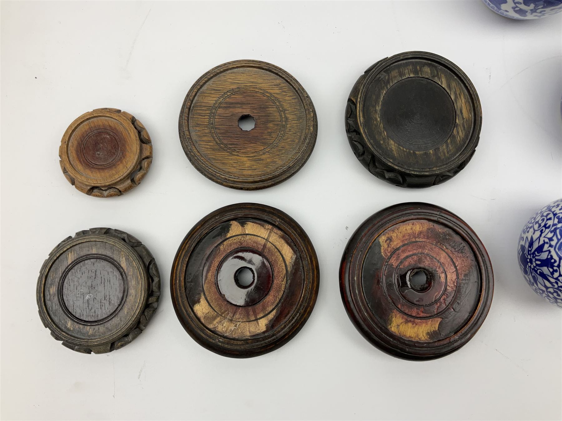Six Chinese ginger jars, predominantly of blue and white design decorated with blossoming branches, all with lids, housed on various hardwood carved stands, some with character marks beneath