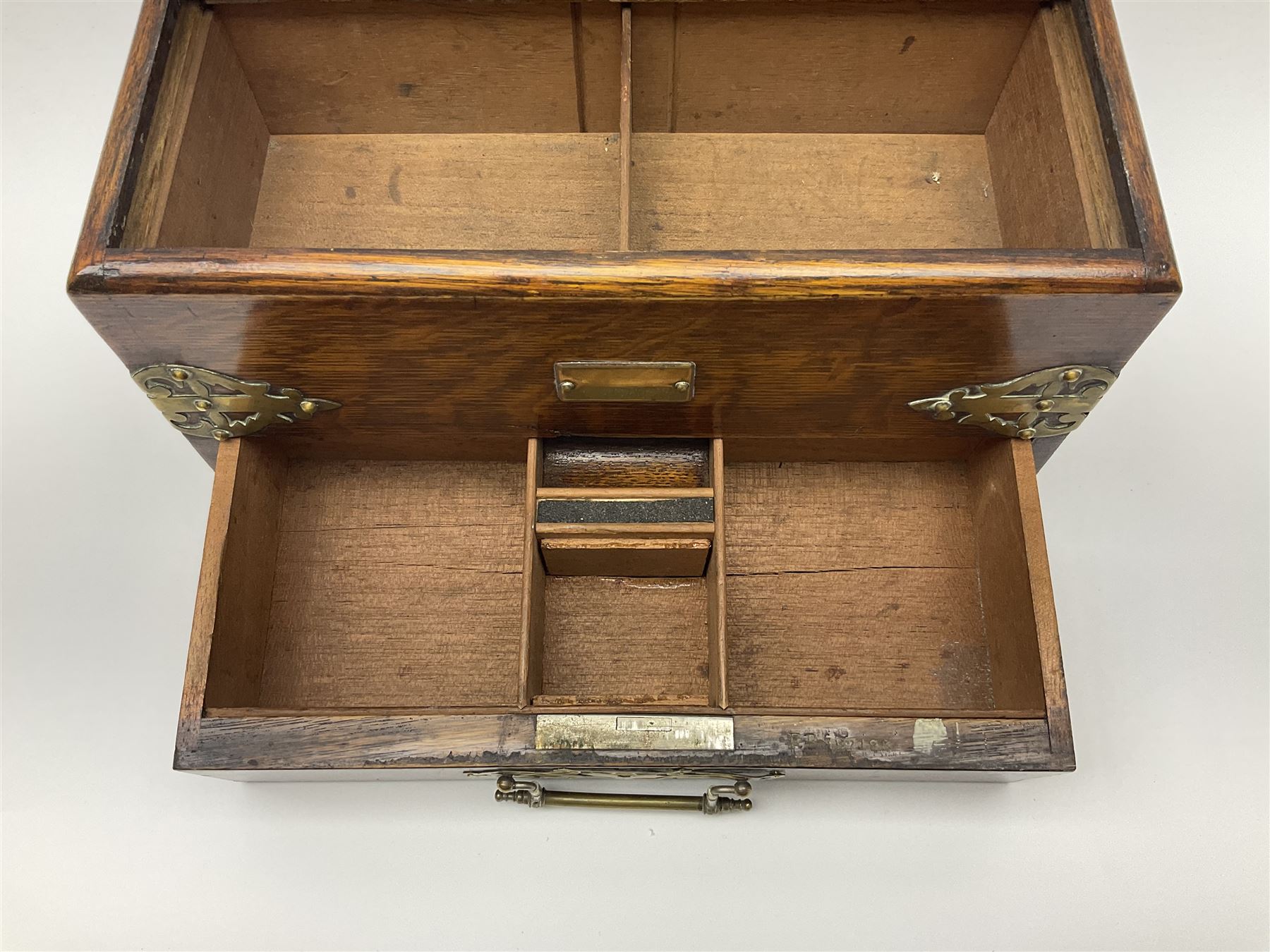 Brass mounted oak humidor, the slide action top opening to a base drawer, cedar lined with central compartment and striker, the drawer stamped Rd 107198, H17cm, D18cm