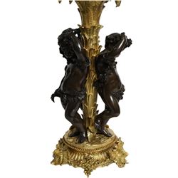 Louis XVI style gilt table lamp, the central column decorated with acanthus leaves, surrounded with three putti with vine leaf crowns, upon a circular base adorned with grape and vines, with shade, H64cm