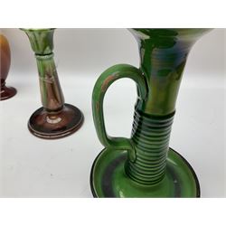 Linthorpe pottery vase with crimped rim and ovoid body, Linthorpe jug with high loop handle and crimped spout, a pair of candlesticks with a green, brown glaze and other similar pottery 
