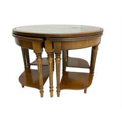 Yew wood circular coffee table with four nesting tables, inset leather and glass tops, on turned and fluted supports