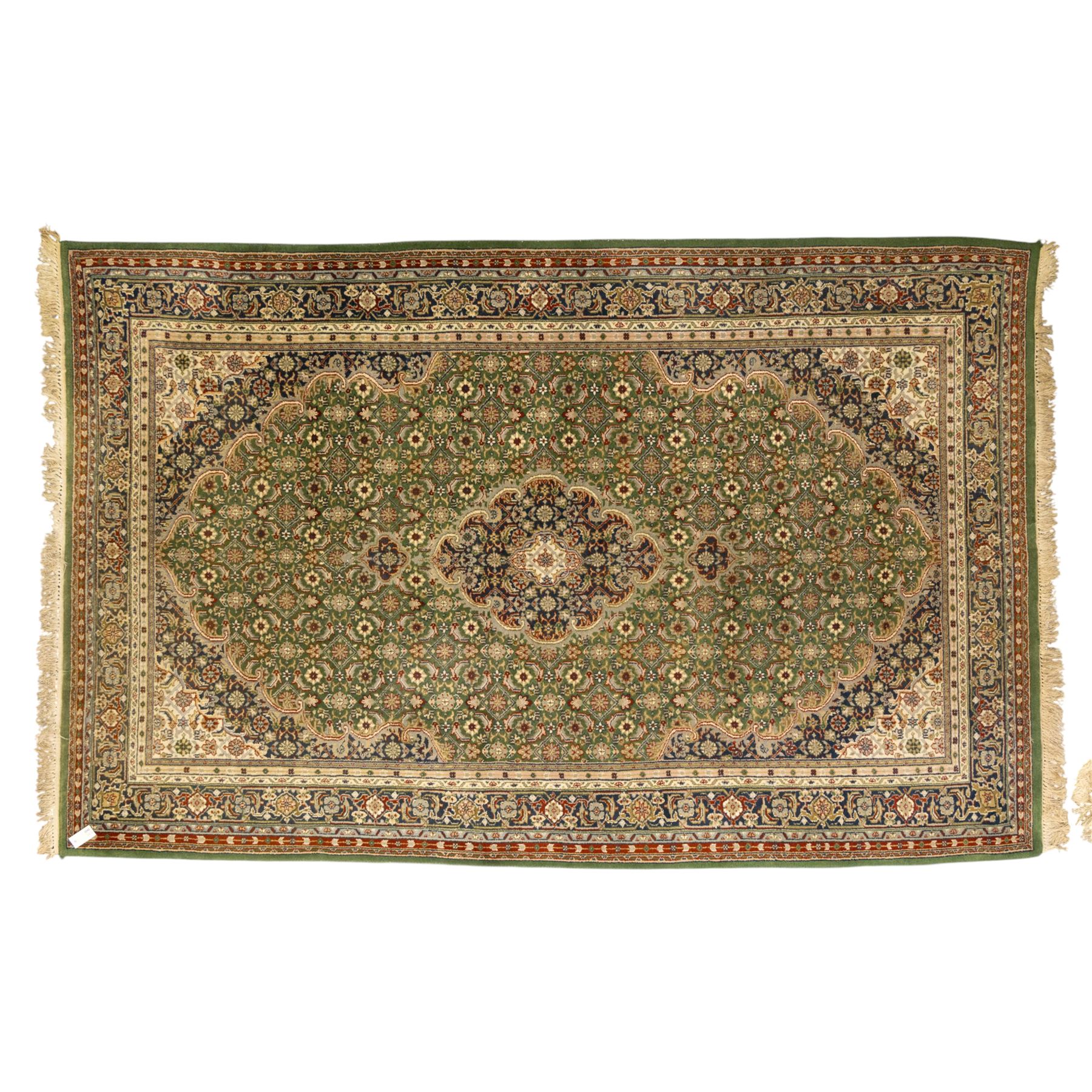 Central Persian Kashan rug, emerald green ground, with a central ivory, indigo, and brick red lobbed medallion with pendant finials, ivory spandrels, framed by multiple floral borders