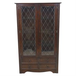 Mid 20th century oak display cabinet, the moulded rectangular cornice above a pair of leaded glazed doors with diamond lattice glazing, enclosing adjustable shelving, the lower section fitted with four short drawers with brass ring handles, flanked by chamfered uprights with carved leaf detail