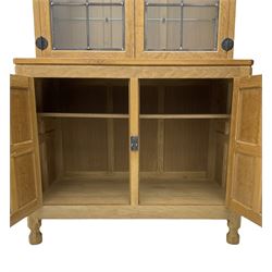 'Mouseman' oak display cabinet on cupboard, raised cabinet enclosed by two lead glazed doors, adzed oak top over double panelled cupboard, fitted with ironwork and carved with mouse signature, by Robert Thompson of Kilburn