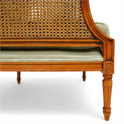 French Empire design varnished wood three piece lounge suite comprising of two cane armchairs and matching sofa, carved top rails with foliate terminals, cane side panels and padded scroll arms, upholstered in a green brocade with matching piping, on fluted legs