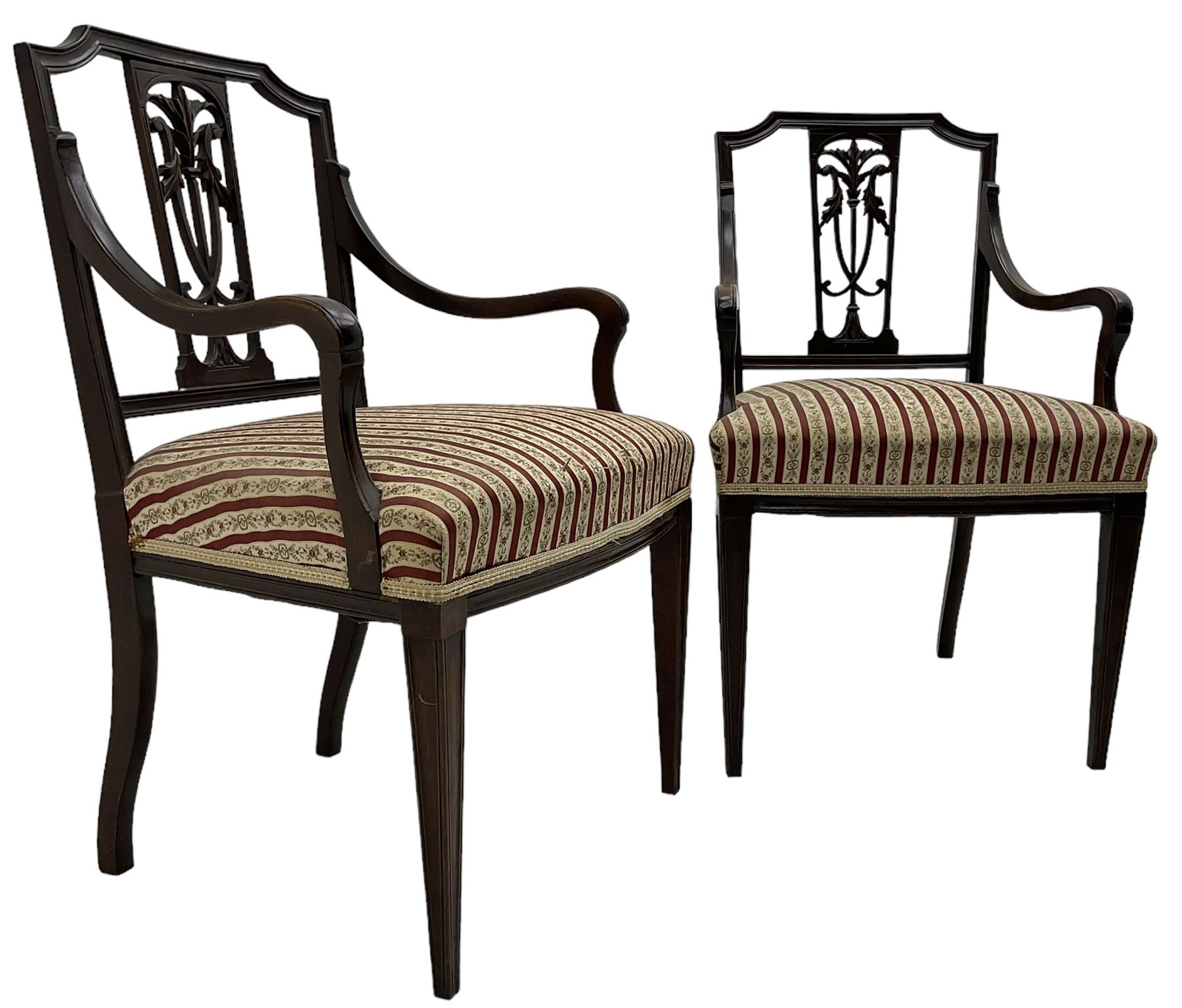 Edwardian mahogany framed three-piece salon suite - two-seat sofa, stepped cresting rail over acanthus and scroll carved pierced splat, upholstered in striped fabric (W124cm, H87cm, D62cm); and a pair of matching armchairs (W60cm) 