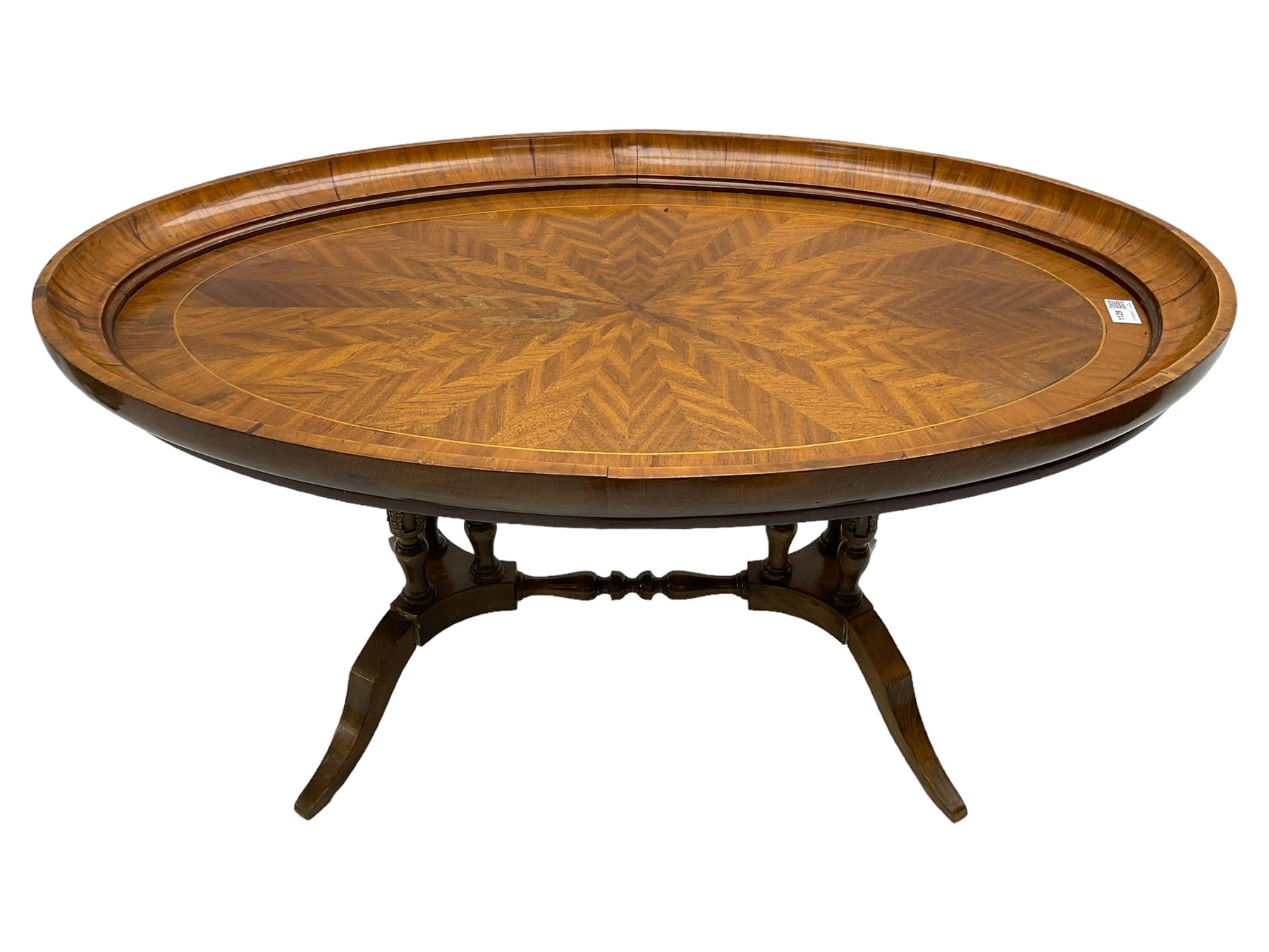 Early 20th century walnut coffee table, oval dished top with sunburst matched veneer, raised on twin cluster columns united by turned stretcher base on splayed supports