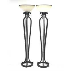 Pair of black painted metal floor standing uplighter lamps, each of skeletal form with three clusters of scrolling tubular supports on circular base with upturned semi-circular mottled glass shade H182cm
