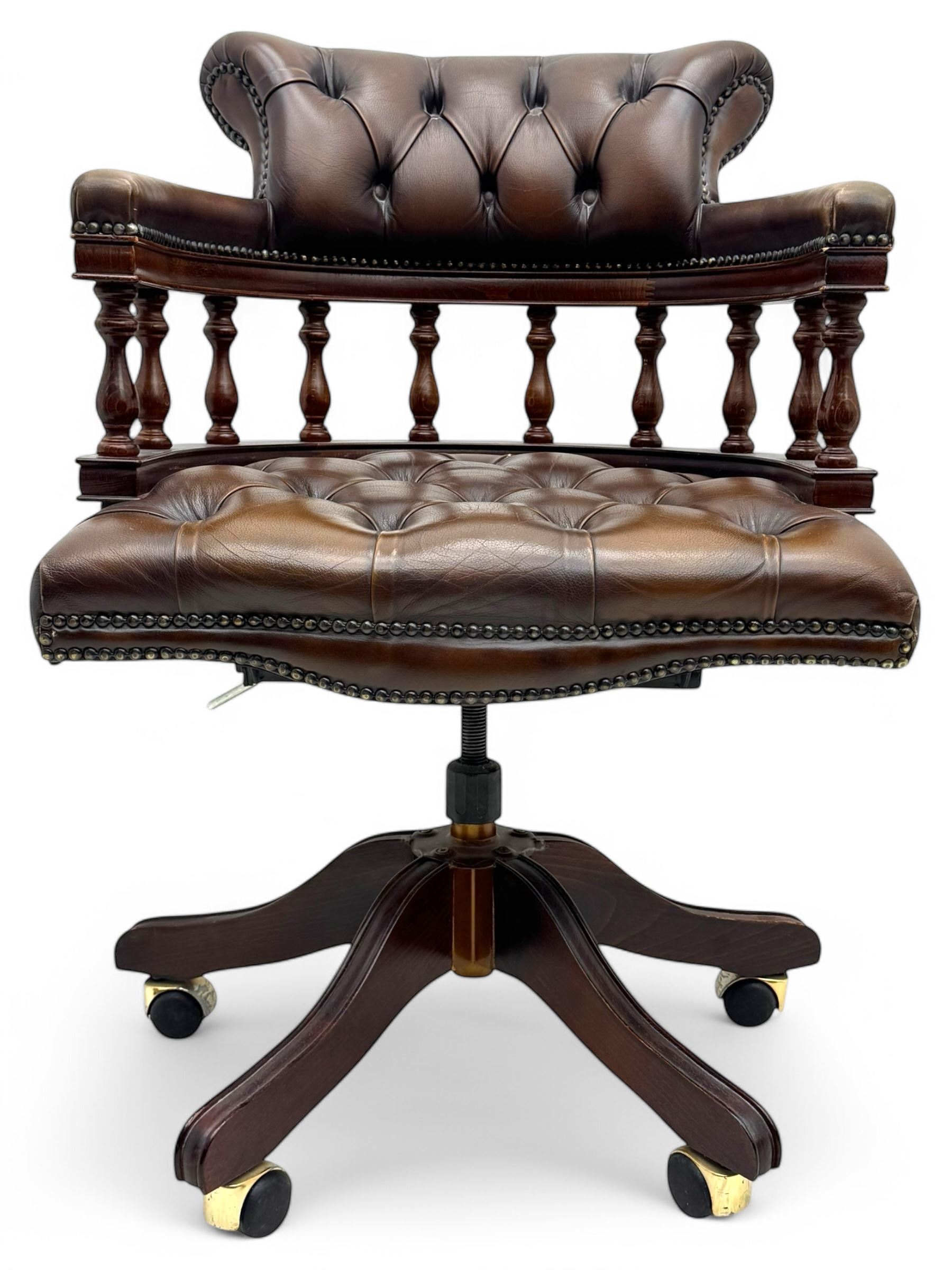 Mahogany framed swivel Captains desk chair, upholstered in brown buttoned leather, turned supports and swivel base on castors