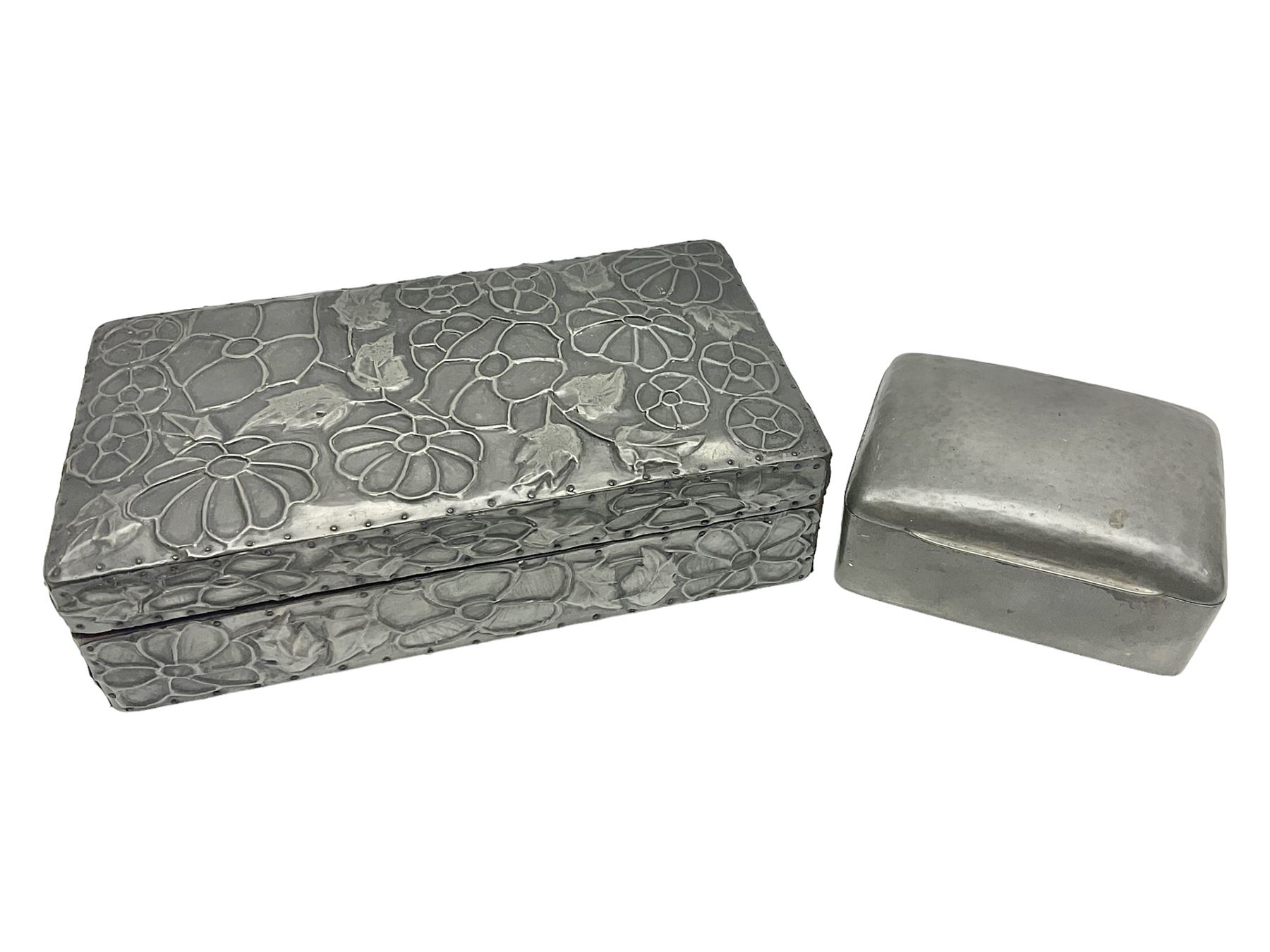 Liberty & Co Tudric pewter cigarette box, of plain rectangular form, with planished decoration to the slightly domed cover, opening to reveal a softwood interior, stamped Made in England 01234 Tudric Solkets beneath, together with another cigarette box, with applied pewter panels repousse decorated throughout with flower heads and leaves, with compartmentalised softwood interior, largest H5.5cm, W23cm